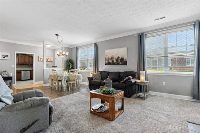 living room featuring crown molding, an inviting chandelier, visible vents, and baseboards