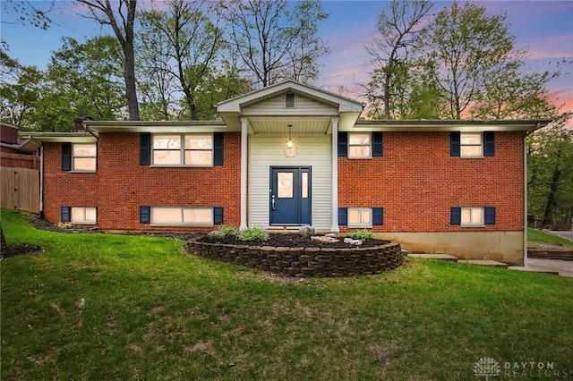 split foyer home with a front yard and brick siding
