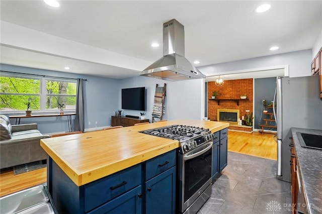 kitchen featuring wooden counters, island exhaust hood, appliances with stainless steel finishes, and open floor plan