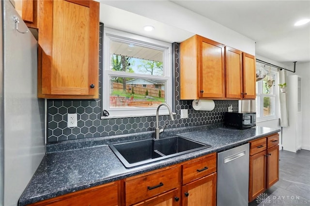 kitchen featuring tasteful backsplash, black microwave, stainless steel dishwasher, and a sink