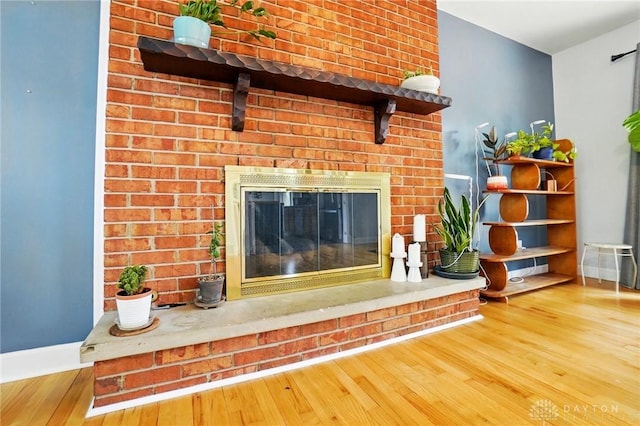 room details featuring a brick fireplace, wood finished floors, and baseboards