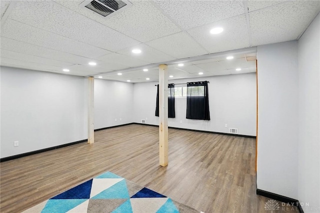 basement with wood finished floors, visible vents, and baseboards