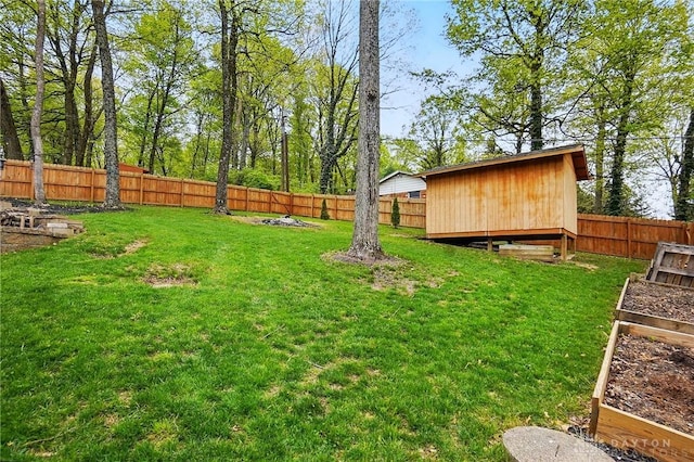view of yard featuring an outdoor structure, a fenced backyard, and a garden