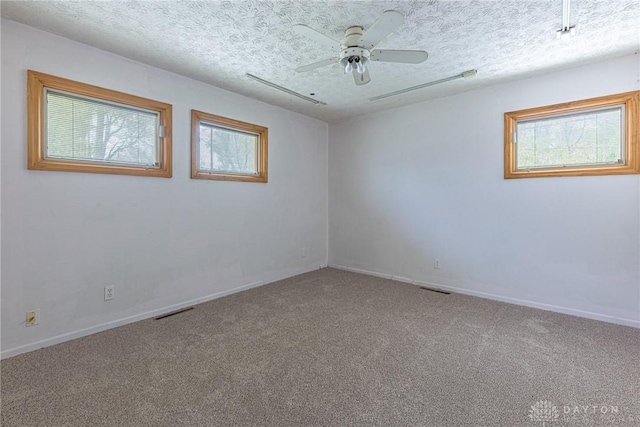carpeted empty room with baseboards, visible vents, and a ceiling fan