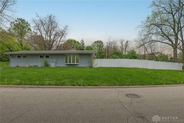 view of property exterior featuring a lawn, fence, and a chimney