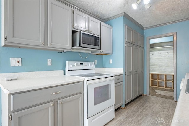 kitchen featuring stainless steel microwave, light countertops, a textured ceiling, and white electric stove