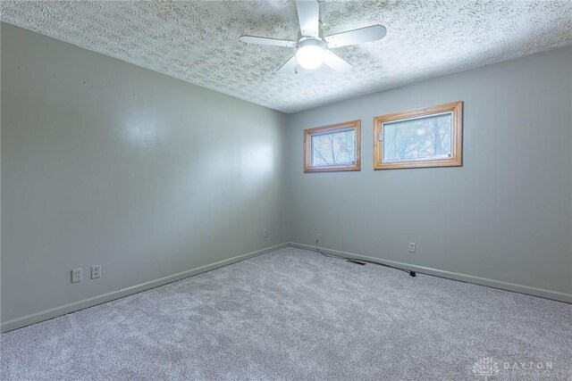 unfurnished room with a textured ceiling, a ceiling fan, carpet, and baseboards