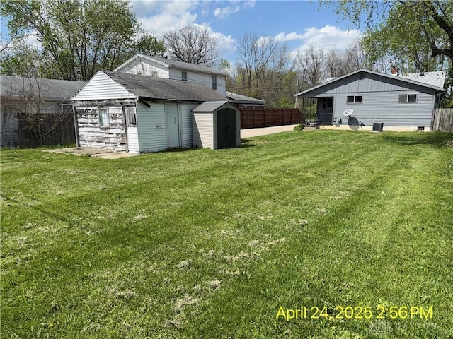 view of yard with a fenced backyard, a shed, and an outbuilding
