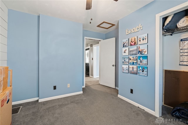 unfurnished bedroom featuring carpet, a ceiling fan, attic access, visible vents, and baseboards