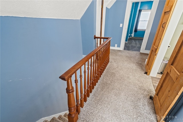 stairs with a textured ceiling, carpet flooring, and baseboards