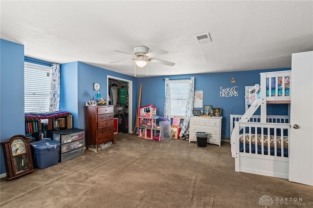 carpeted bedroom with a ceiling fan, visible vents, and a textured ceiling