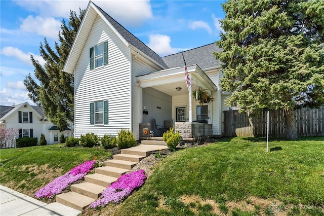 view of front of property featuring a shingled roof, a porch, fence, and a front yard