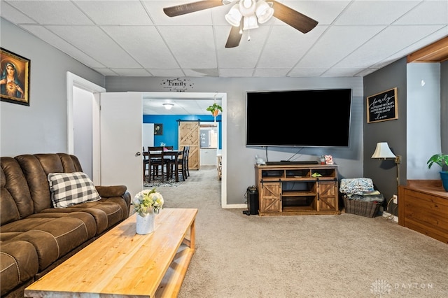 living room featuring a paneled ceiling, carpet floors, a ceiling fan, and baseboards