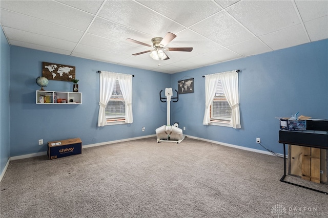 interior space featuring a paneled ceiling, carpet, a ceiling fan, and plenty of natural light