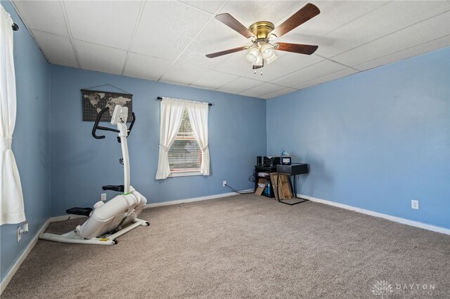 exercise room featuring carpet flooring, baseboards, a ceiling fan, and a paneled ceiling