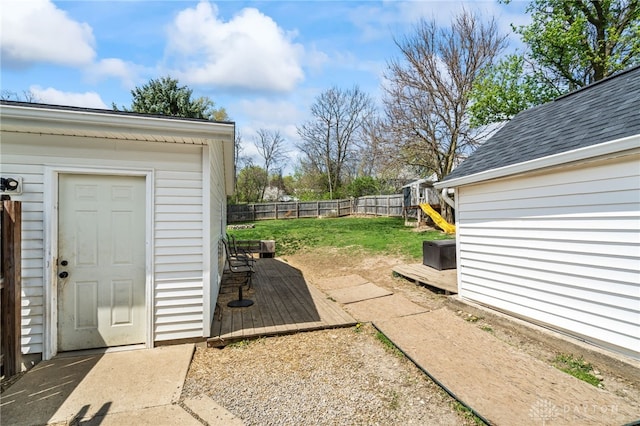 view of yard featuring a playground, an outdoor structure, a deck, and a fenced backyard