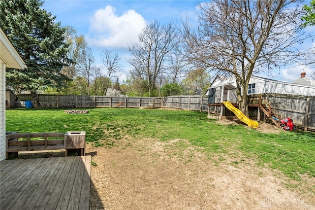 view of yard featuring a playground, a wooden deck, and a fenced backyard