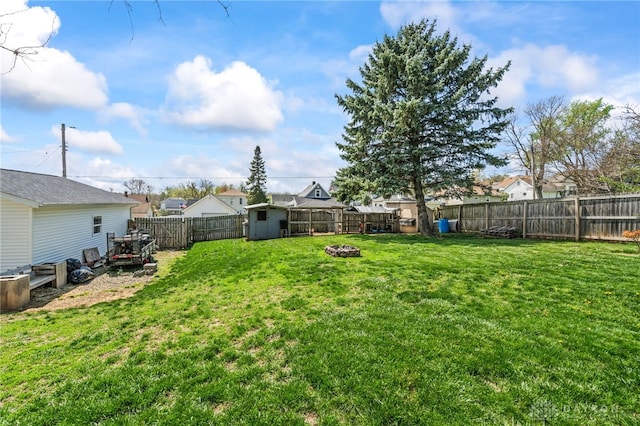 view of yard featuring an outdoor structure, a fire pit, a fenced backyard, and a storage unit