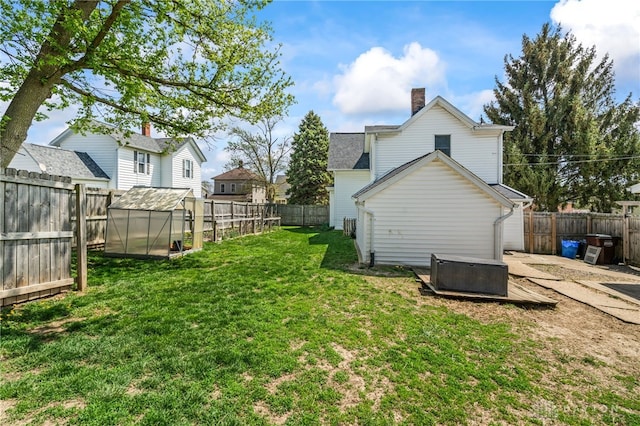 view of yard featuring a greenhouse, an outbuilding, and a fenced backyard