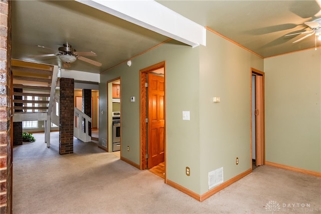 carpeted empty room featuring crown molding, ceiling fan, baseboards, and visible vents