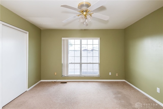 carpeted empty room with visible vents, ceiling fan, and baseboards