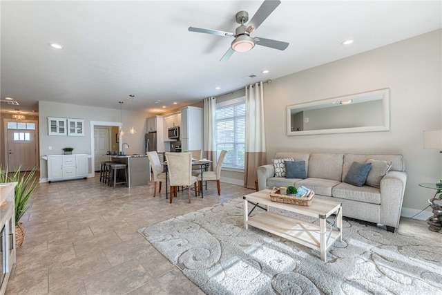 living area featuring recessed lighting, ceiling fan, stone finish floor, and baseboards