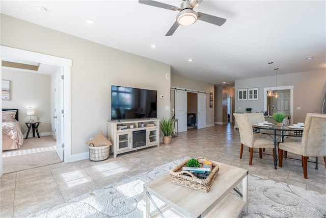 living room with a barn door, a ceiling fan, recessed lighting, and baseboards