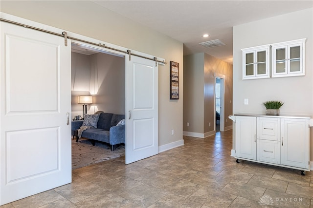 interior space featuring a barn door, recessed lighting, visible vents, and baseboards