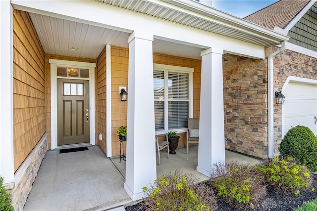 entrance to property featuring a garage, covered porch, roof with shingles, and stone siding
