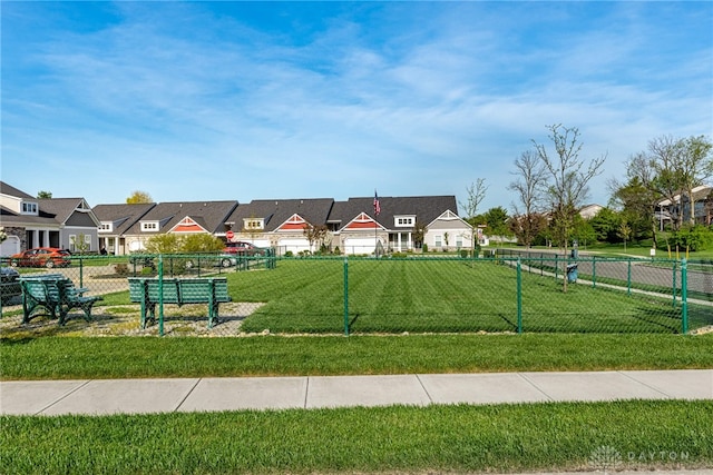 view of property's community with fence, a yard, and a residential view