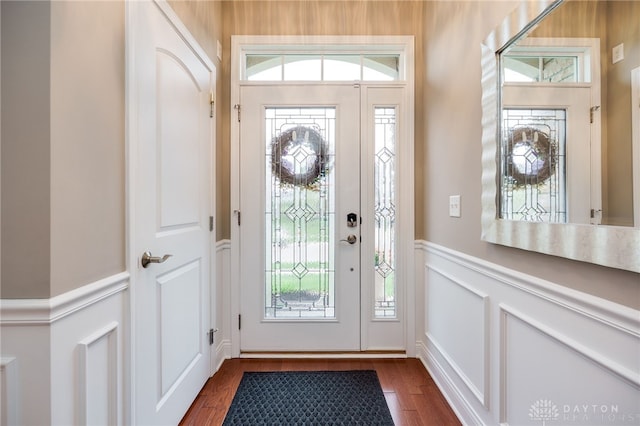 entrance foyer featuring dark wood-style flooring, wainscoting, a wealth of natural light, and a decorative wall