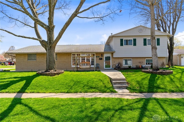 tri-level home with brick siding and a front yard