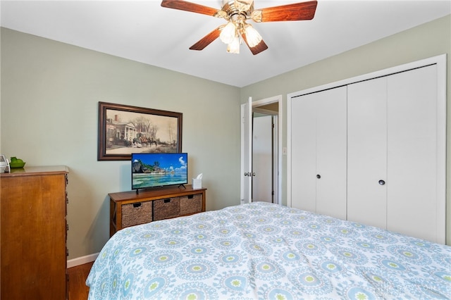 bedroom with baseboards, wood finished floors, a ceiling fan, and a closet