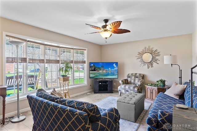 living area featuring ceiling fan, plenty of natural light, and baseboards