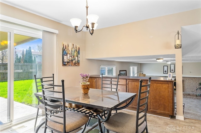 dining space with an inviting chandelier, a wealth of natural light, visible vents, and light wood finished floors