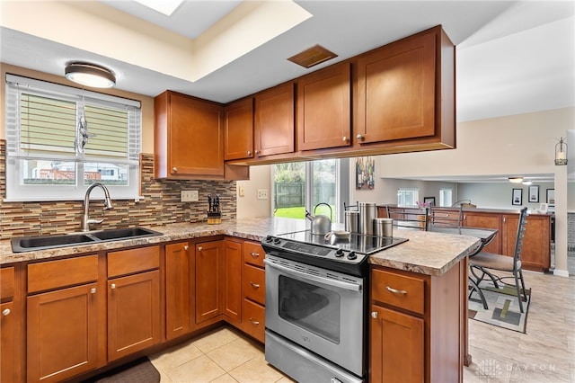 kitchen with brown cabinets, a sink, stainless steel electric range, a peninsula, and light countertops