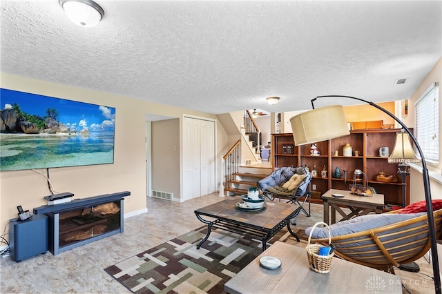 living area with a textured ceiling, visible vents, and stairs