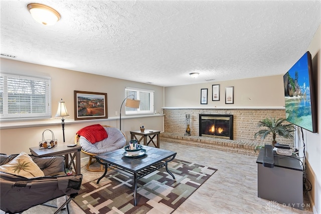 living room with a textured ceiling, visible vents, and a brick fireplace