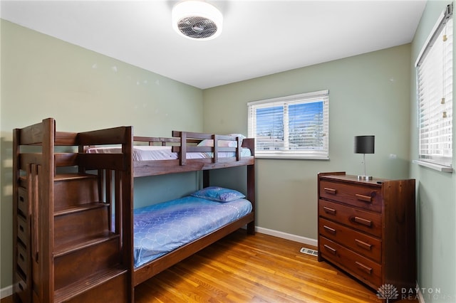 bedroom with visible vents, wood finished floors, and baseboards