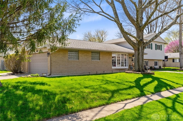 tri-level home featuring an attached garage, concrete driveway, a front yard, and brick siding