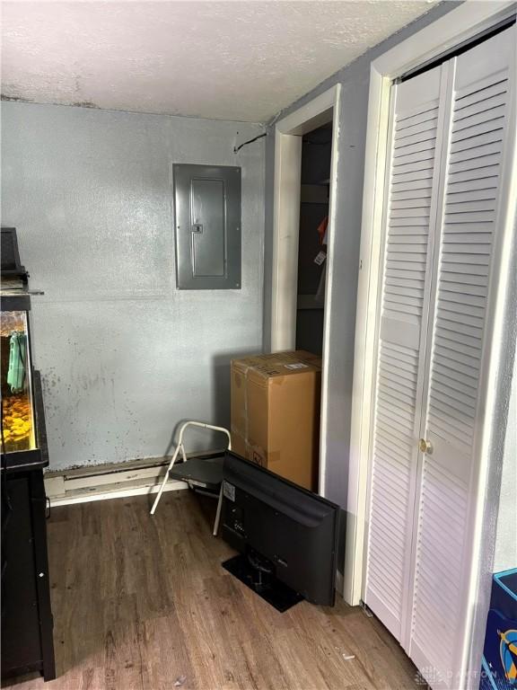 bedroom featuring wood finished floors, a textured ceiling, electric panel, and a closet