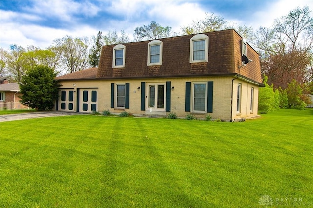 cape cod house with concrete driveway, roof with shingles, a front yard, mansard roof, and a garage