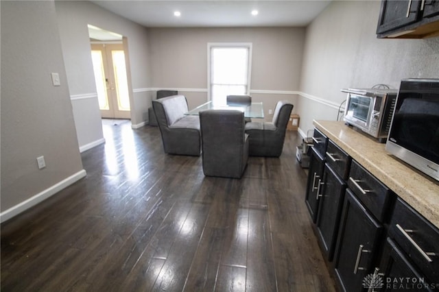 dining room featuring a toaster, plenty of natural light, dark wood-style flooring, and baseboards