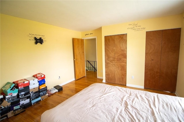 bedroom featuring multiple closets, wood finished floors, and baseboards
