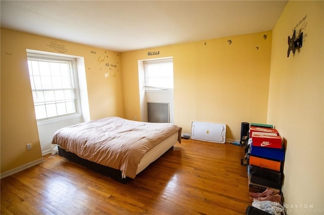 bedroom featuring hardwood / wood-style flooring, baseboards, and multiple windows
