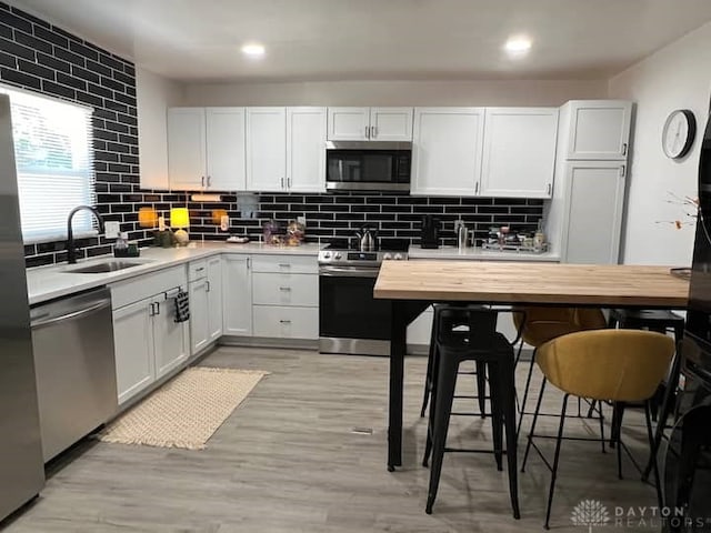 kitchen with light countertops, a sink, stainless steel appliances, and decorative backsplash