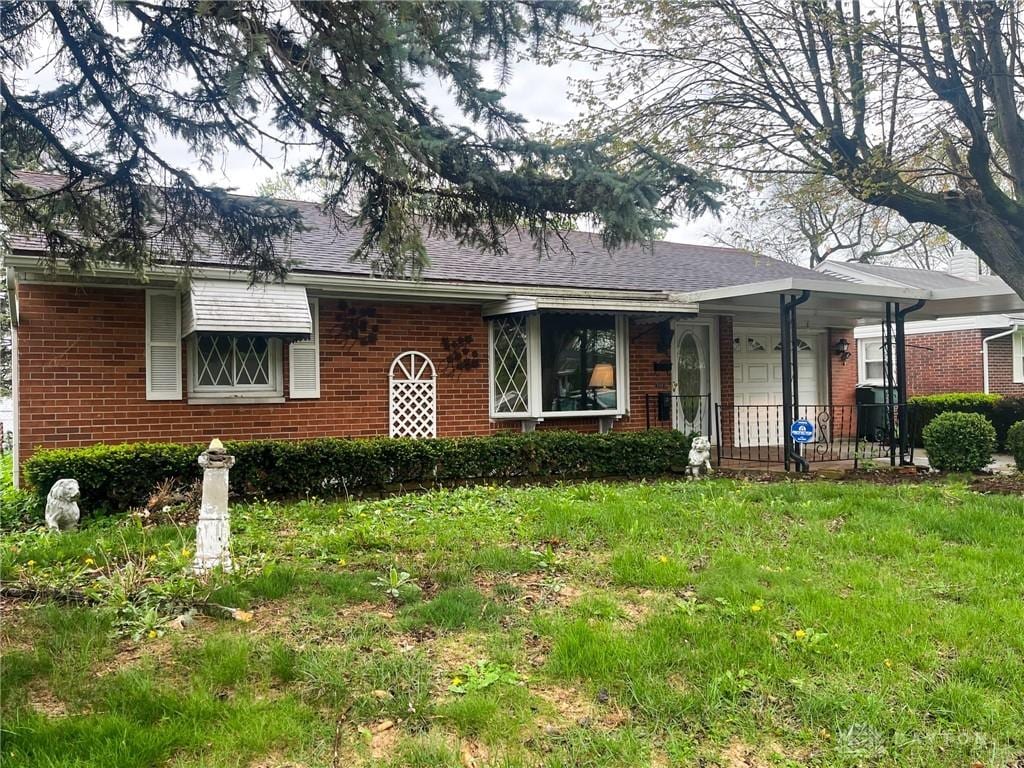 view of front facade with a front yard and brick siding