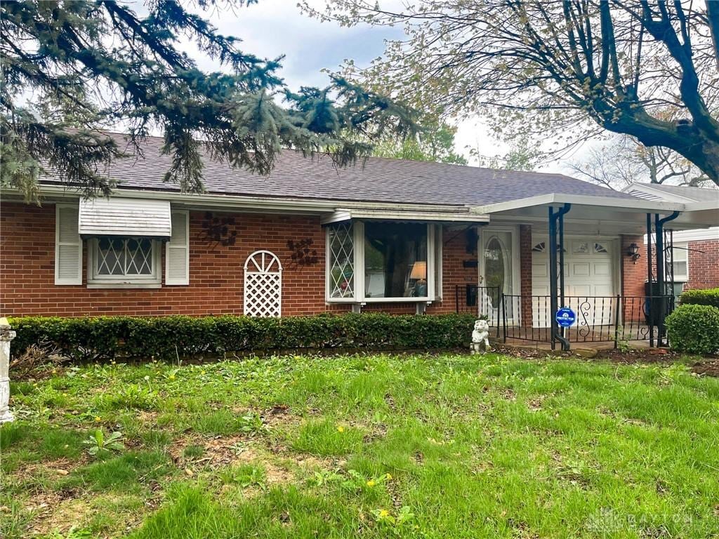 ranch-style house with a front lawn, an attached garage, and brick siding