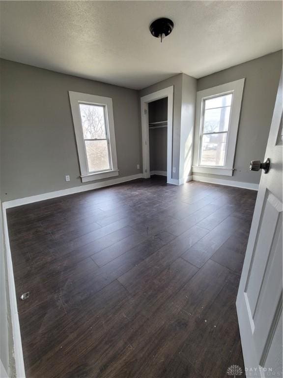 66 Barnett St Unit 64, Dayton, OH 45402 - unfurnished bedroom featuring dark wood finished floors, baseboards, a textured ceiling, and a closet
