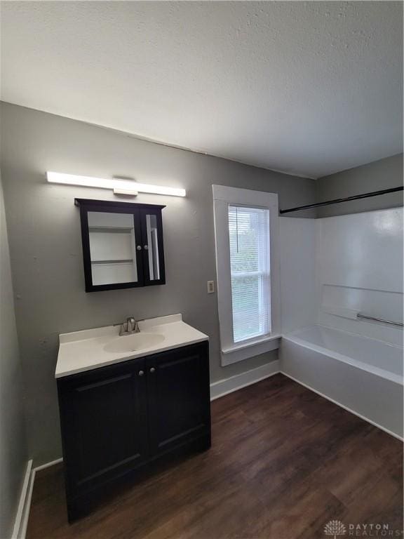 66 Barnett St Unit 64, Dayton, OH 45402 - bathroom with baseboards, wood finished floors, vanity, washtub / shower combination, and a textured ceiling